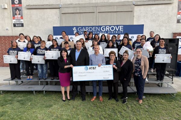 Families holding laptops distributed through the Leading Educational Attainment for Families Initiative, thanks to a generous donation from AT&T